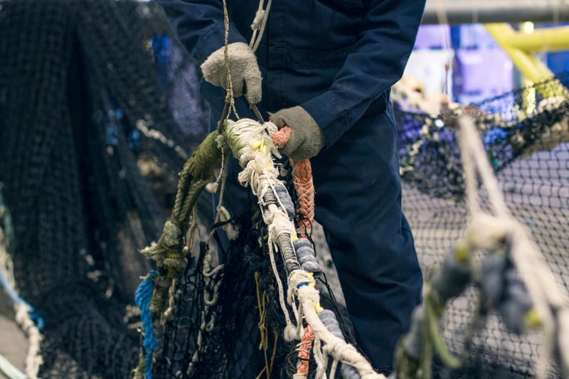 Man pulling old fishing nets out of the water 