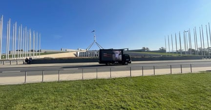 An advertising truck drives past Parliament House in Canberra